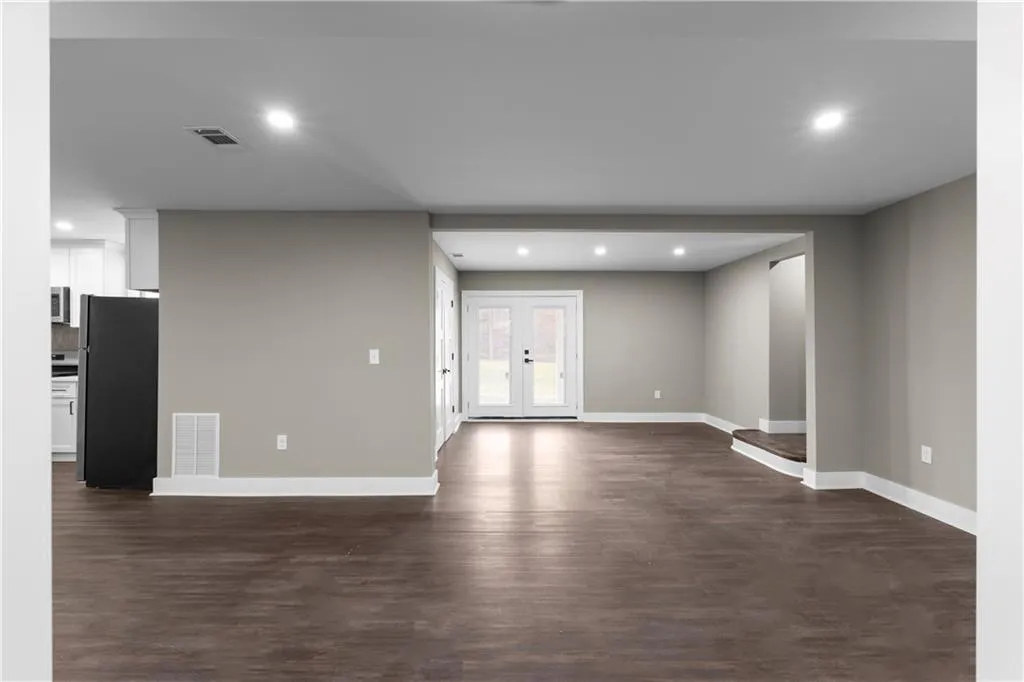 Unfurnished living room with recessed lighting, dark wood-type flooring, and french doors