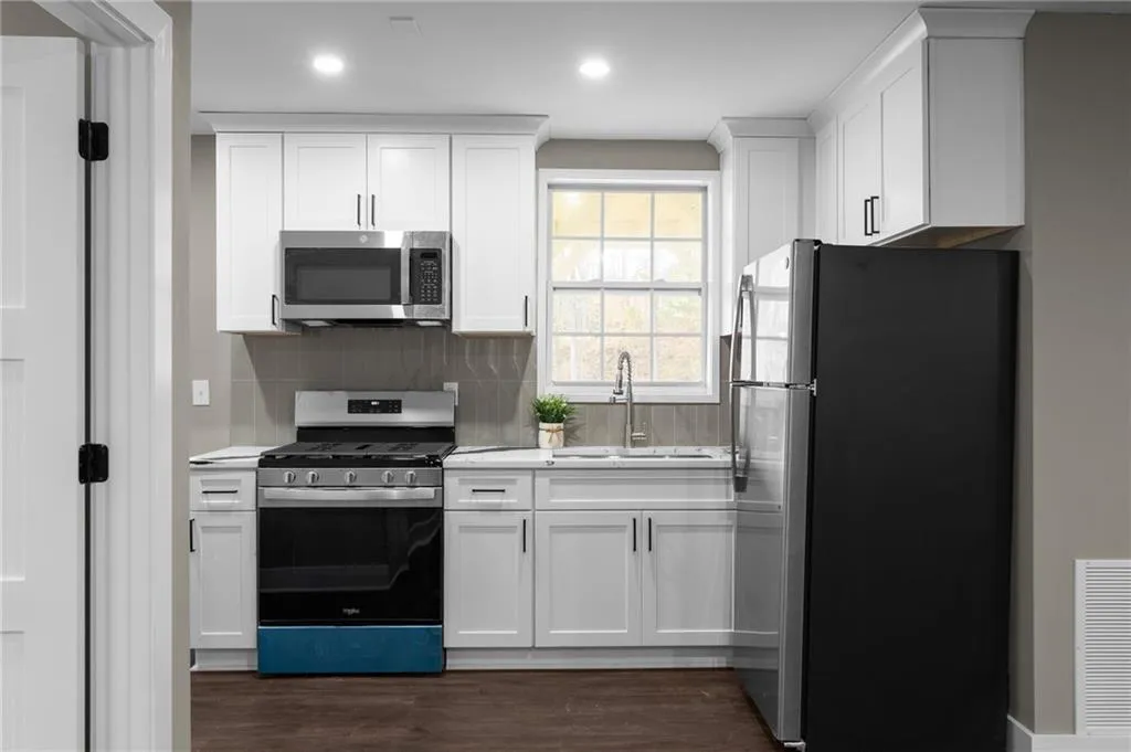 Kitchen with appliances with stainless steel finishes, white cabinetry, decorative backsplash, dark wood-style floors, and recessed lighting