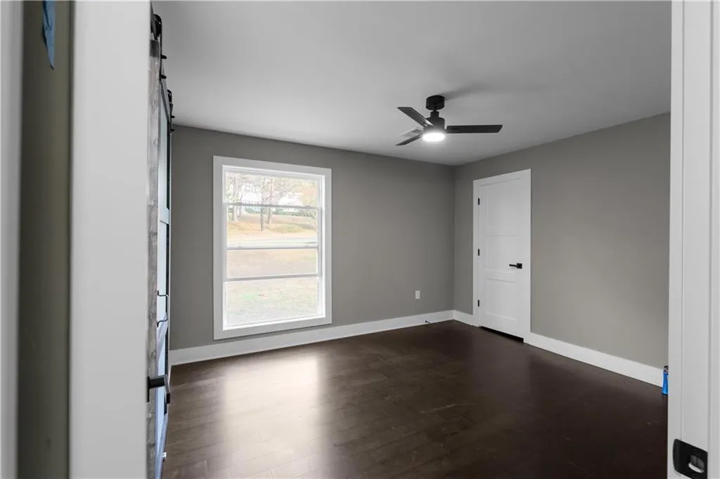 Unfurnished room with dark wood-style flooring and ceiling fan