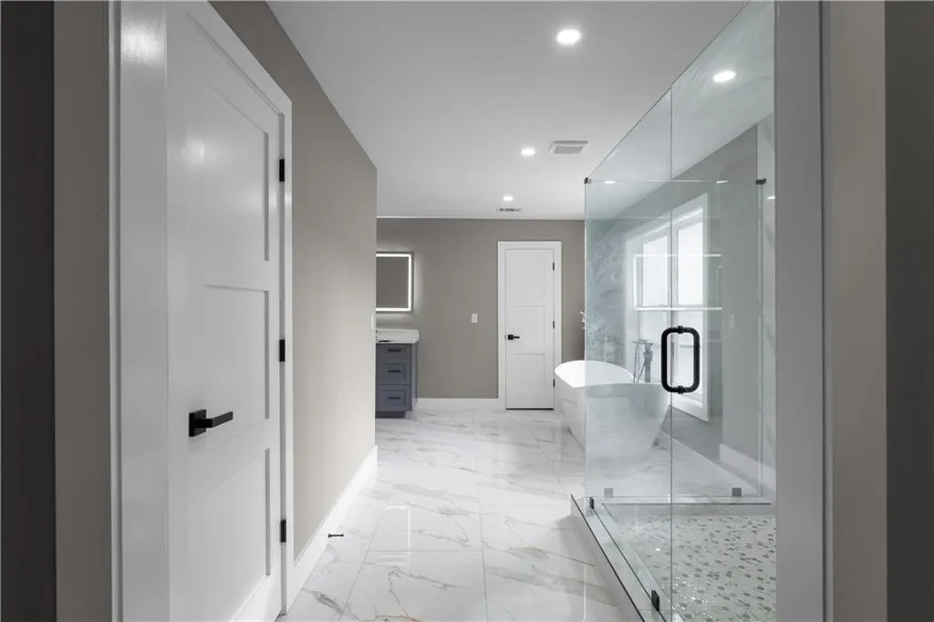 Full bath with a freestanding tub, vanity, a stall shower, light marble finish floors, and recessed lighting