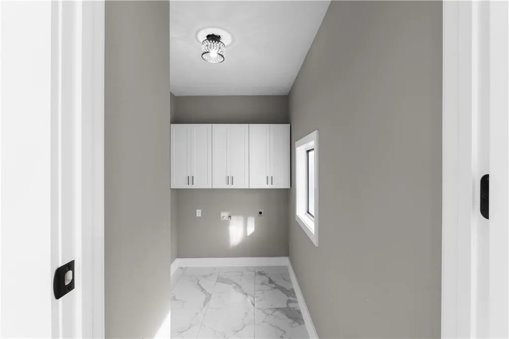 Laundry area featuring light marble finish floors, electric dryer hookup, cabinet space, and washer hookup