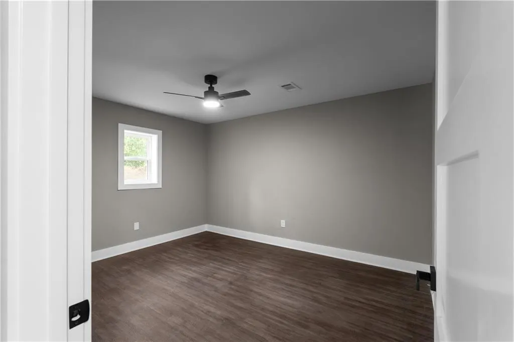 Unfurnished room featuring dark wood-style floors and ceiling fan