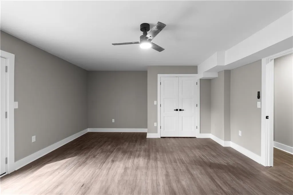 Unfurnished bedroom with a ceiling fan, dark wood-style flooring, and a closet