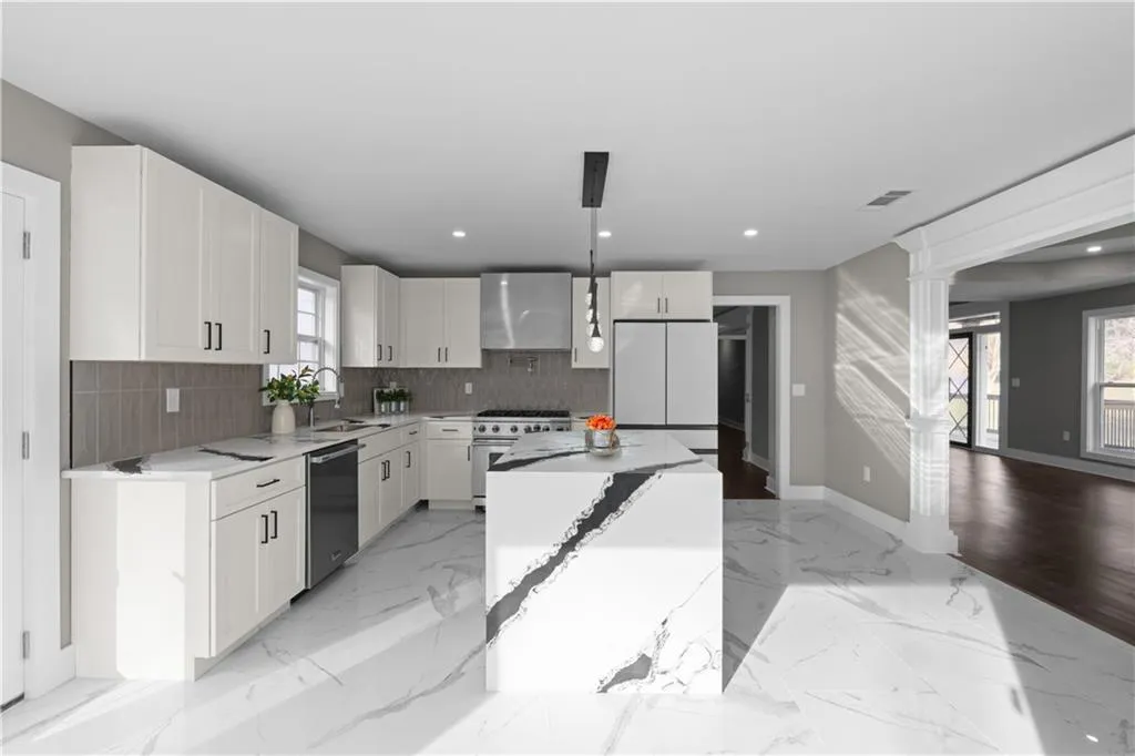 Kitchen featuring hanging light fixtures, white cabinets, light marble finish floors, light stone countertops, and recessed lighting