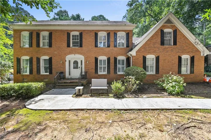 Brick exterior with black shutters and a white-paneled front door