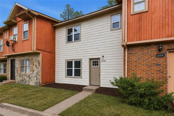 Light-colored horizontal siding exterior with a brown entry door featuring a multi-pane window insert