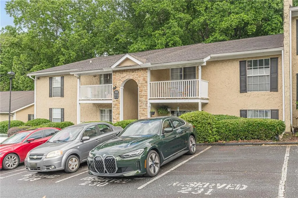 View of front of home featuring stucco siding, uncovered parking, and roof with shingles