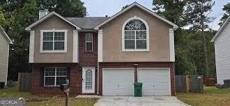Brick and stucco exterior with an arched window, white paneled entry door, and a two-car garage