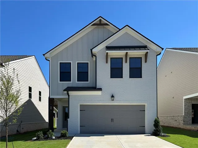 Contemporary-style home featuring a two-story elevation, board and batten siding, painted brick façade, an attached garage, and a concrete driveway