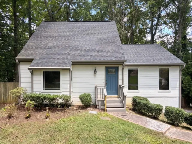 White siding exterior with a blue entry door, multi-pane windows, and a shingled roof