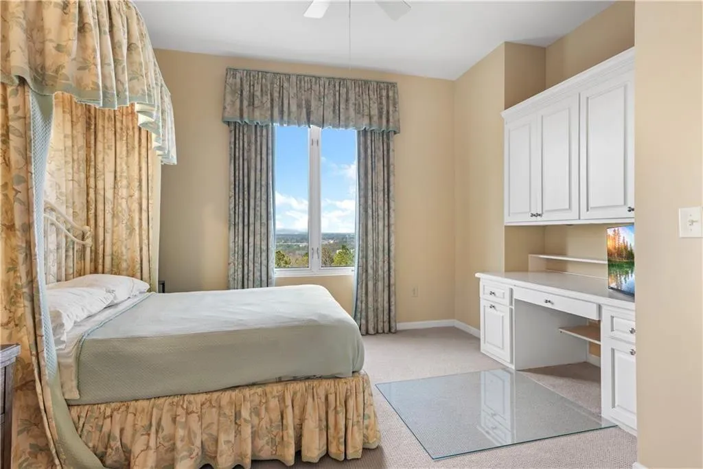 Bedroom with light carpet, a ceiling fan, and built in desk