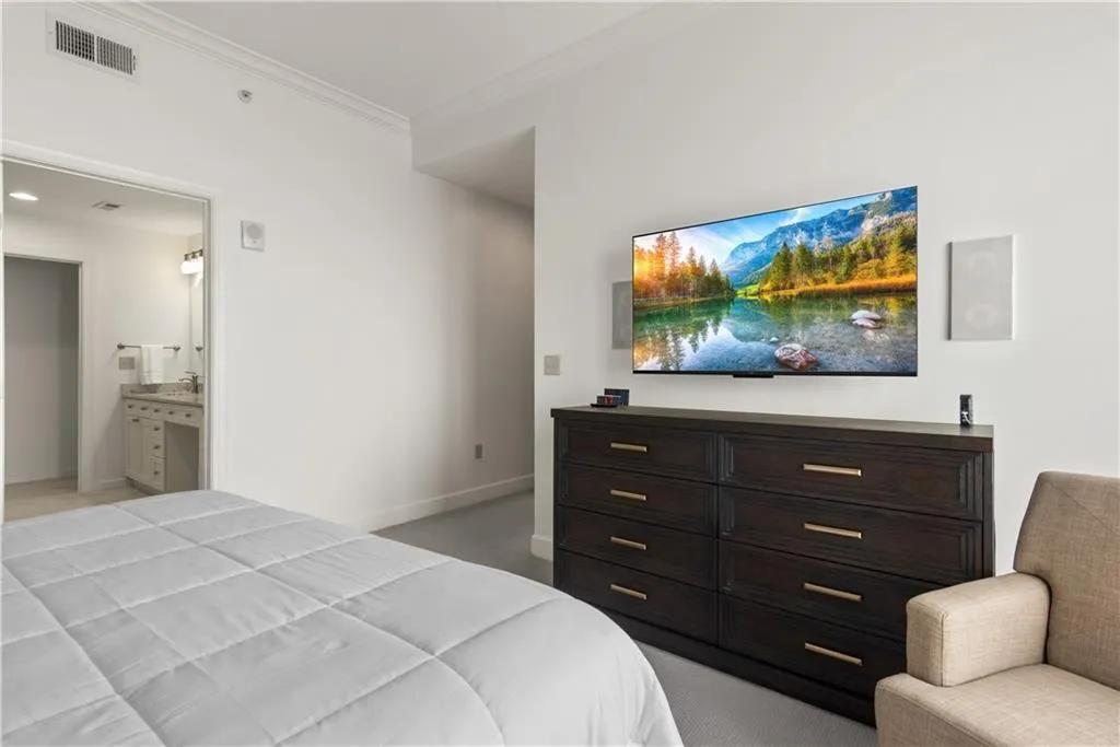 Bedroom featuring crown molding, light carpet, and connected bathroom