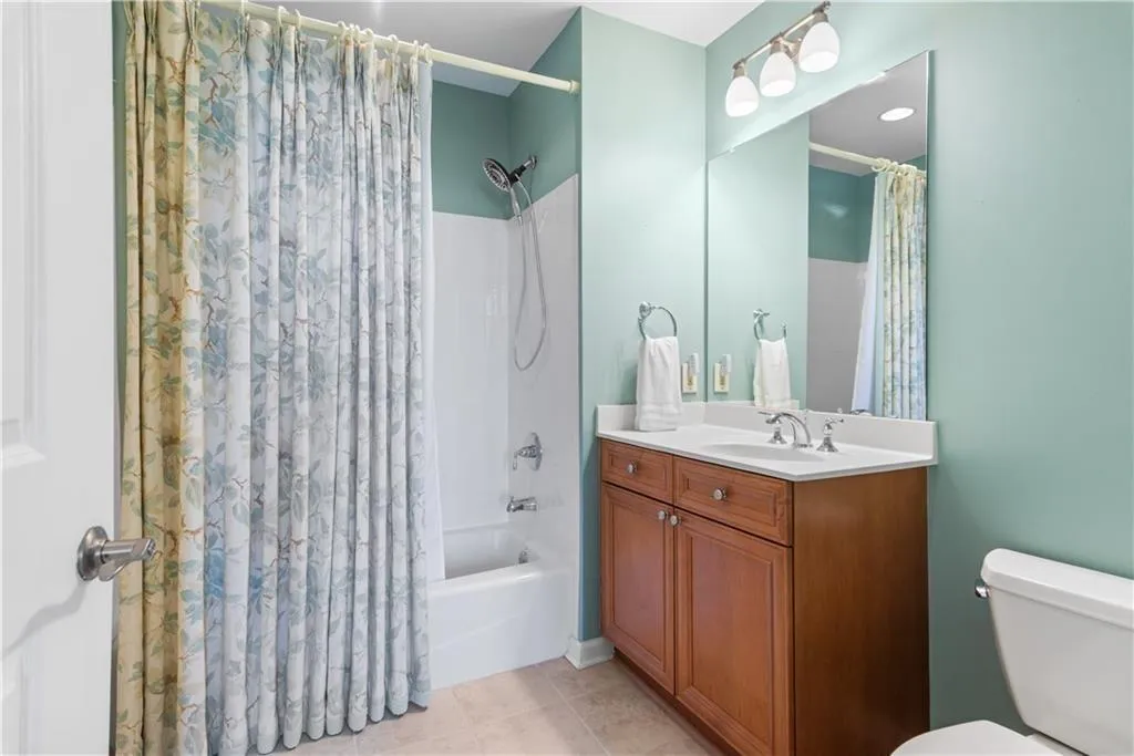 Bathroom with shower / tub combo with curtain, vanity, and light tile patterned floors