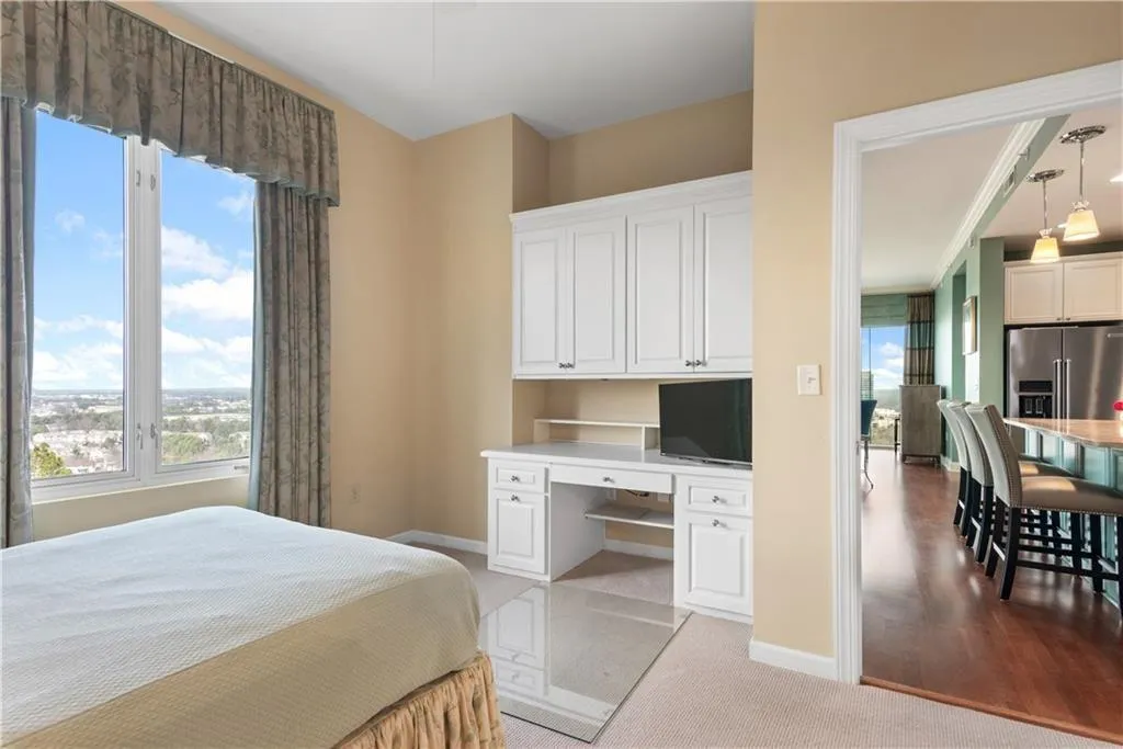 Bedroom featuring built in desk, light colored carpet, and high end refrigerator