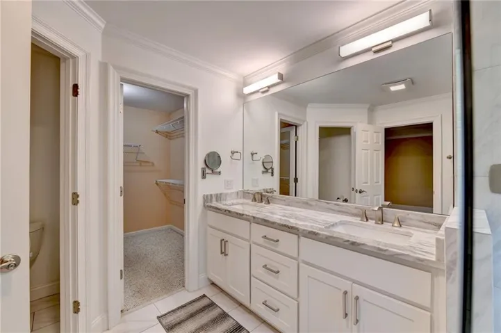 Bathroom featuring a double vanity with a stone countertop, dual undermount sinks, and a full-width mirror