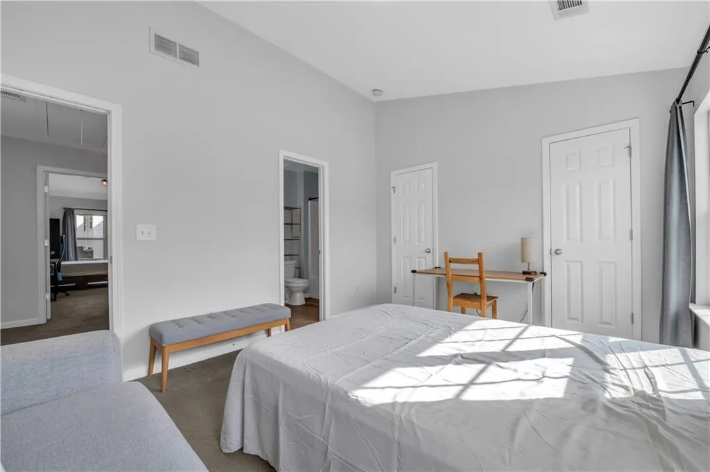 Carpeted bedroom featuring attic access, high vaulted ceiling, and ensuite bath
