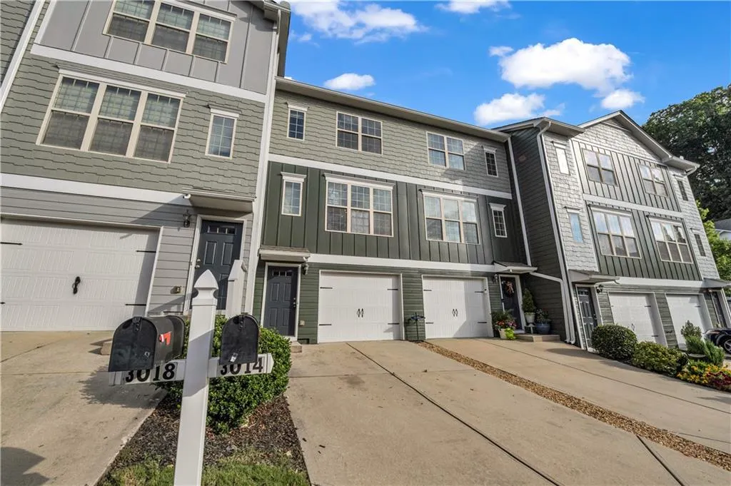 Townhome / multi-family property with board and batten siding, driveway, and an attached garage