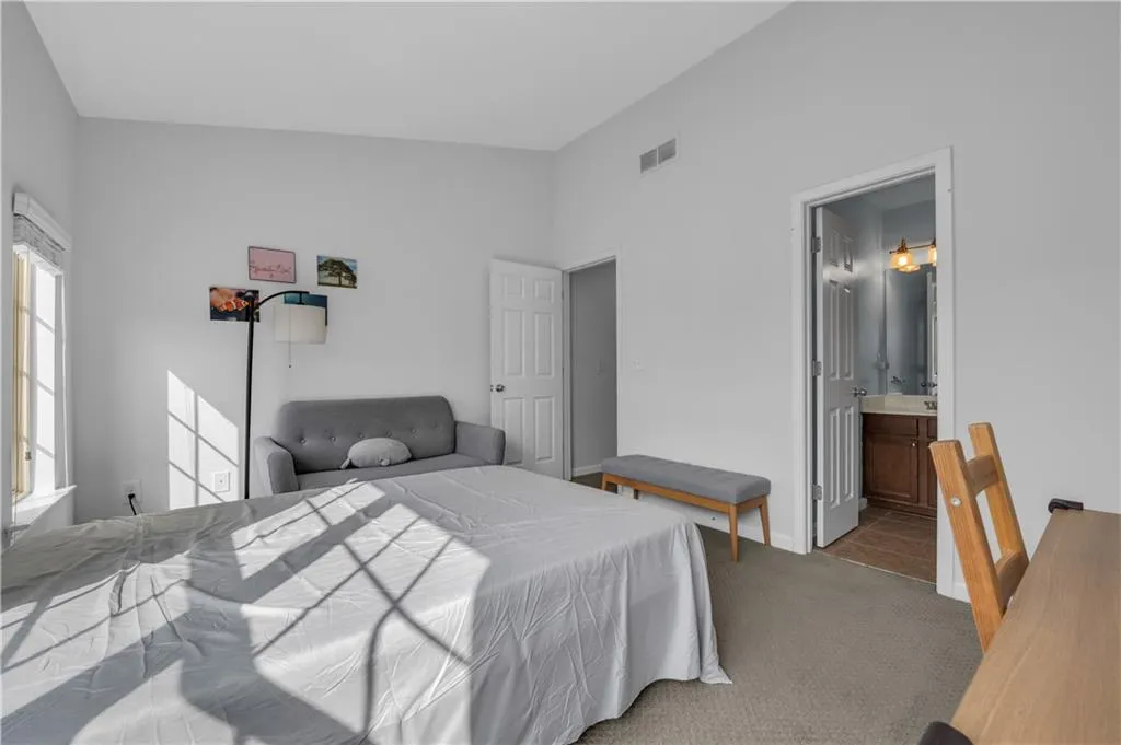 Bedroom featuring carpet, ensuite bathroom, and vaulted ceiling