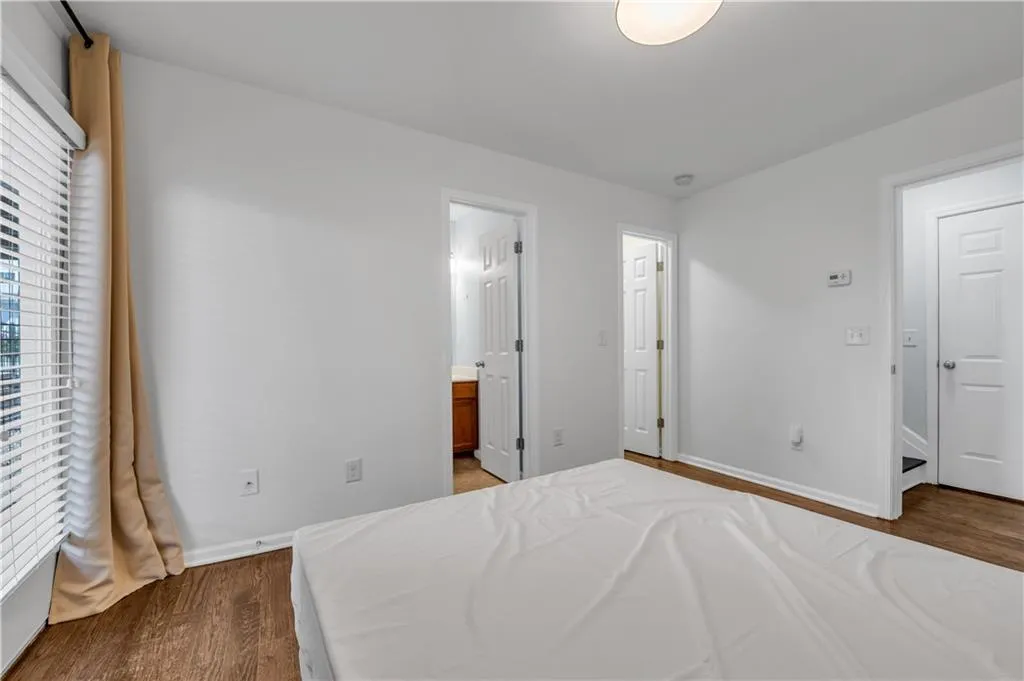 Bedroom with dark wood-style floors and connected bathroom
