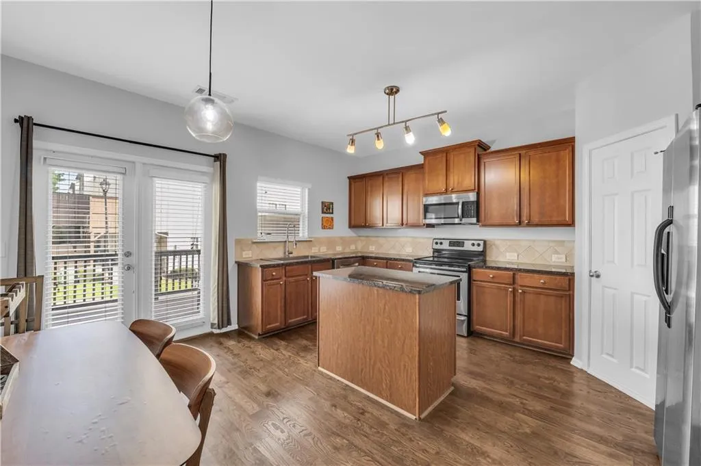 Kitchen featuring appliances with stainless steel finishes, brown cabinets, a center island, and tasteful backsplash