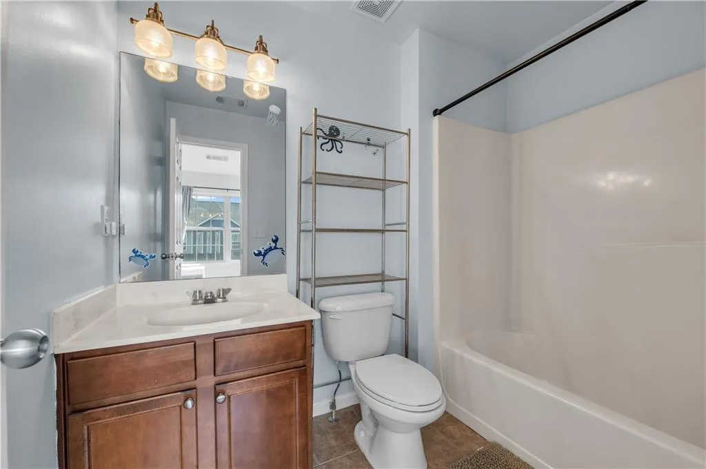 Bathroom featuring vanity, shower / bathtub combination, and tile patterned flooring