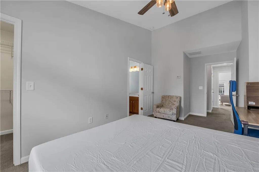 Carpeted bedroom with a walk in closet, ceiling fan, and connected bathroom
