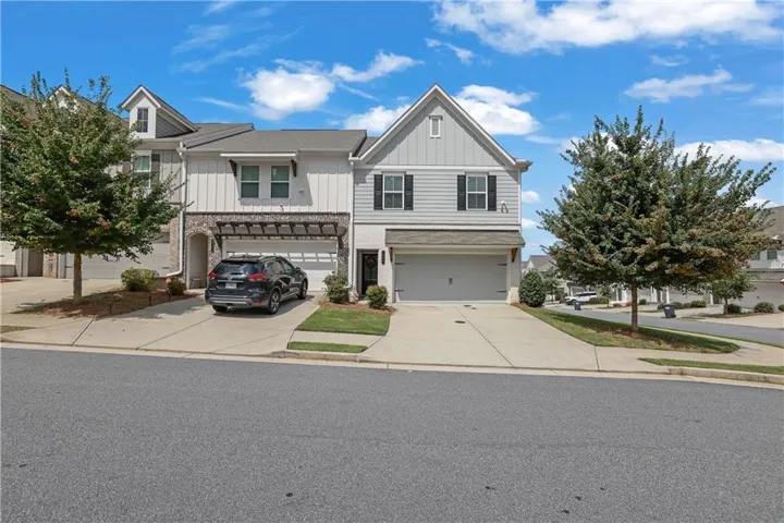 Two-story townhome with light gray siding, a single-car garage, and an additional covered parking space