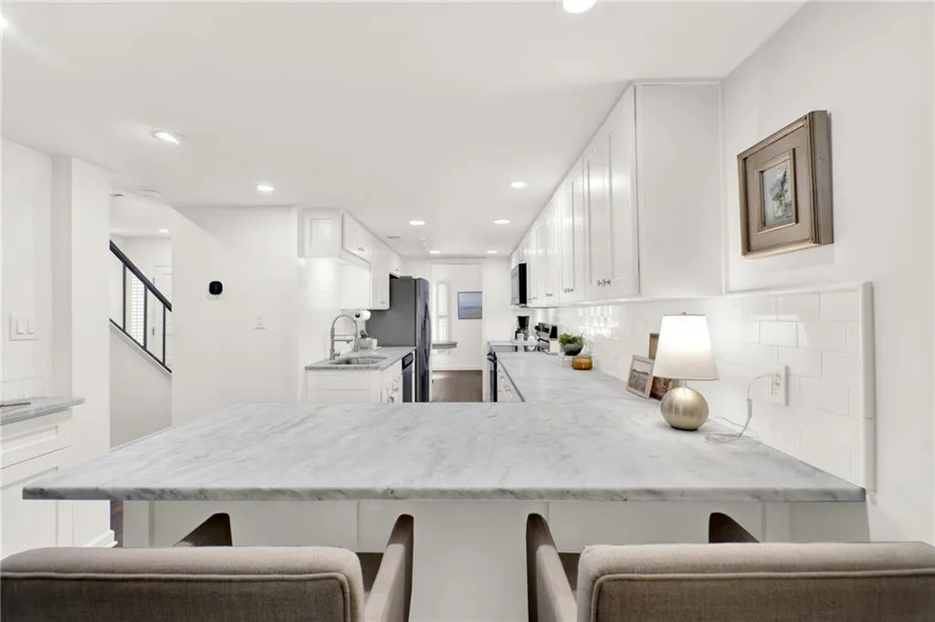 Kitchen featuring stainless steel appliances, a kitchen breakfast bar, decorative backsplash, white cabinets, and a peninsula