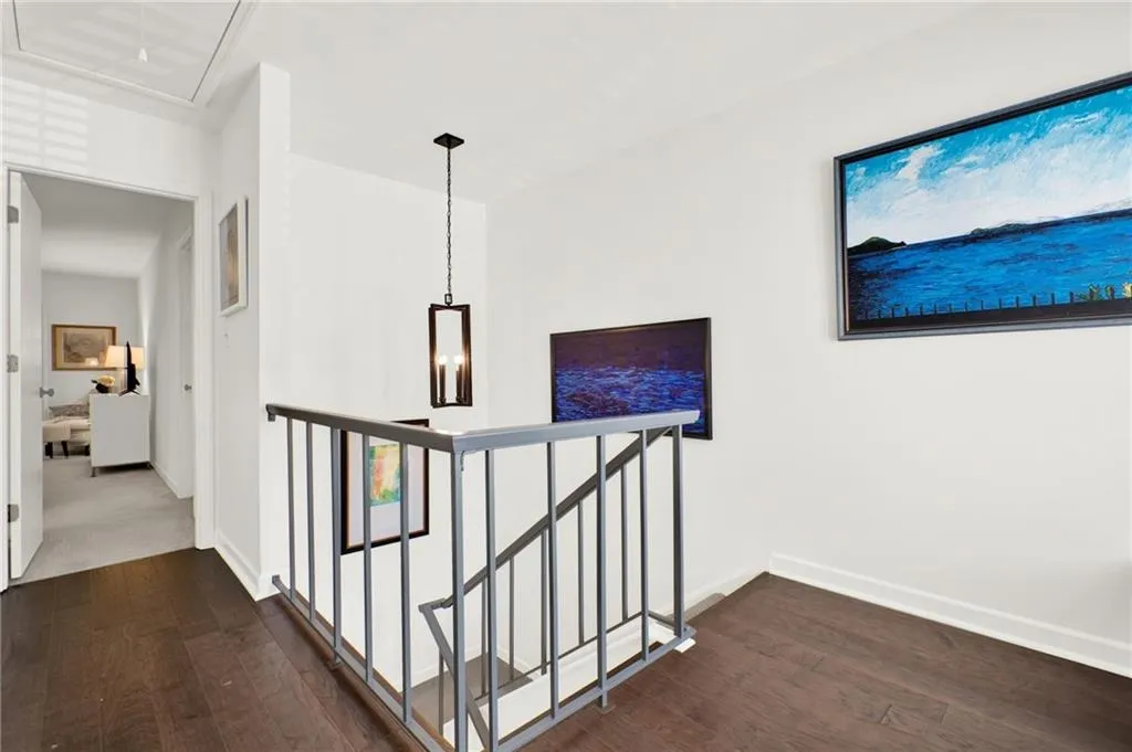 Hallway featuring an upstairs landing, dark wood finished floors, and attic access