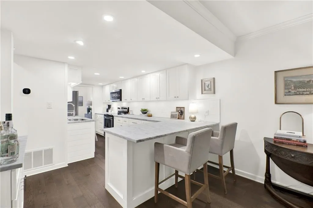 Kitchen featuring stainless steel appliances, white cabinets, a peninsula, crown molding, and dark wood-style floors