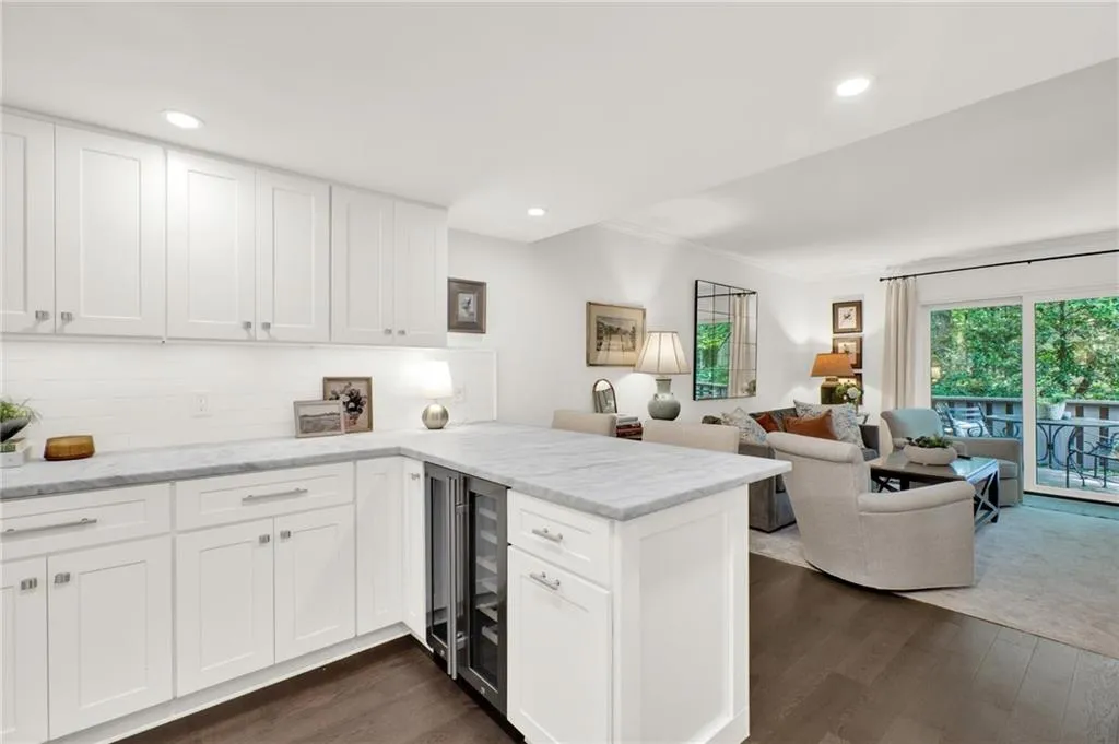 Kitchen featuring a peninsula, dark wood-type flooring, backsplash, white cabinets, and ornamental molding