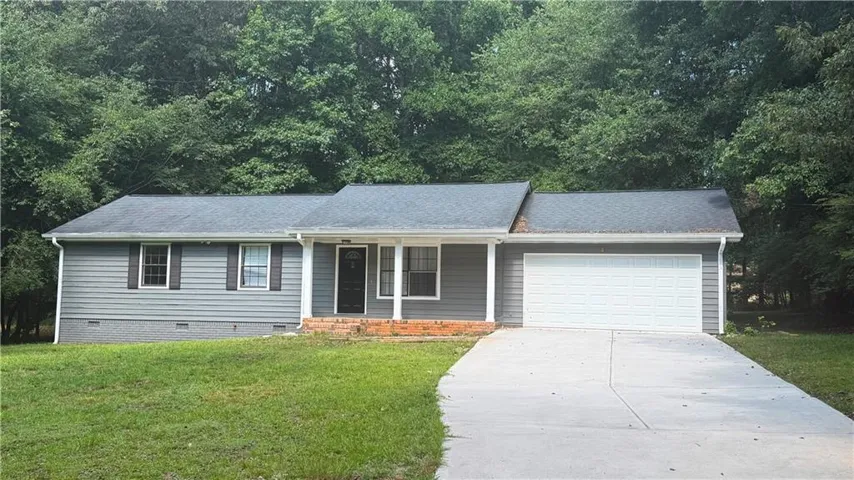 Gray ranch-style home featuring a covered front porch with white columns, a dark front door, and a two-car garage