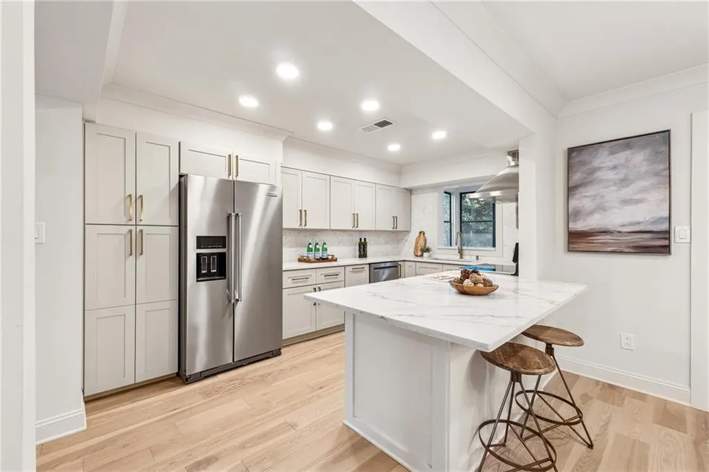 Kitchen with stainless steel appliances, a breakfast bar area, decorative backsplash, light stone counters, and ornamental molding