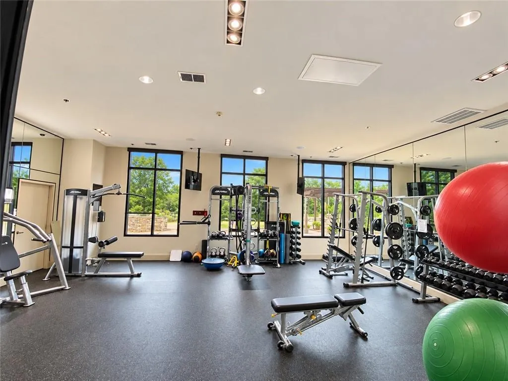 Fitness center with resilient flooring, extensive mirrored walls, recessed lighting, and large windows