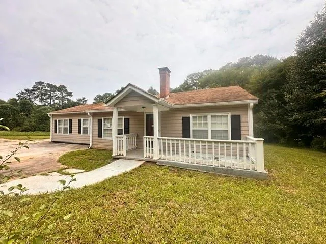 Ranch-style residence featuring a covered front porch, light-colored siding, and a prominent brick chimney