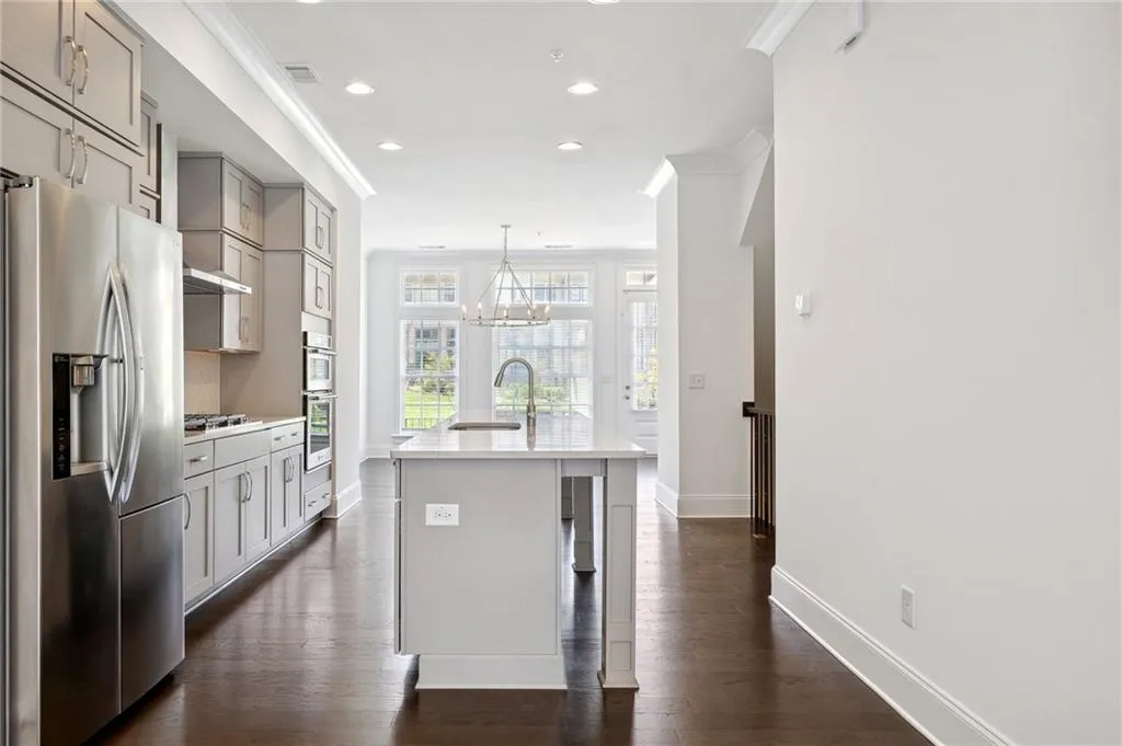 Kitchen with a center island with sink, crown molding, appliances with stainless steel finishes, and dark hardwood / wood-style floors