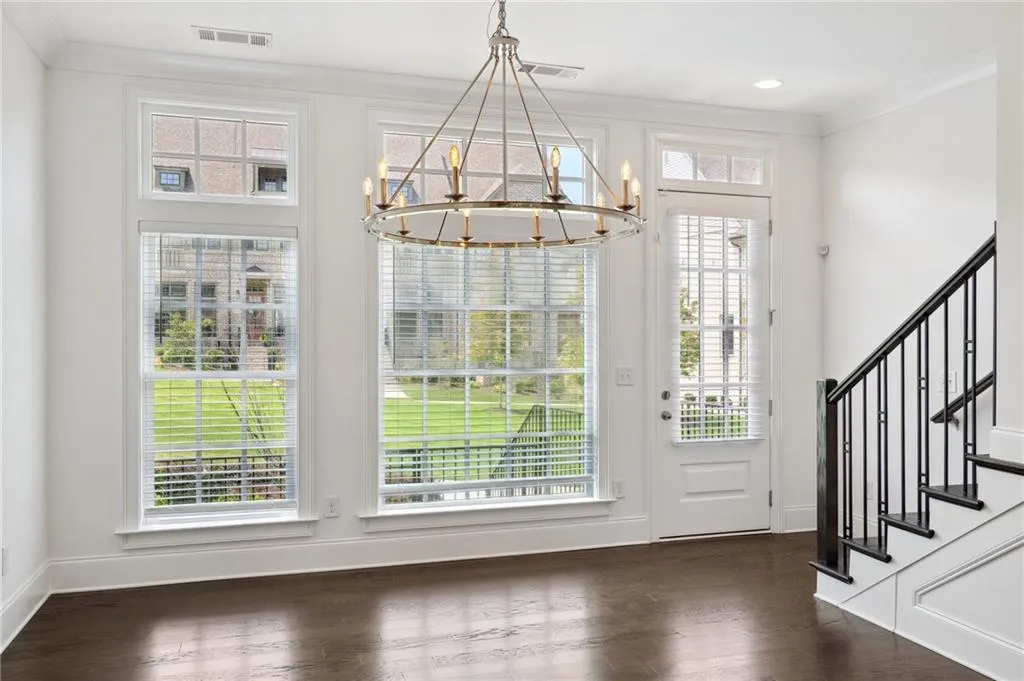 Entrance foyer with crown molding, a wealth of natural light, a chandelier, and dark hardwood / wood-style flooring
