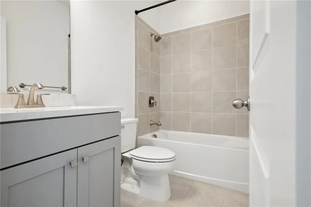 Full bathroom featuring vanity, tiled shower / bath combo, toilet, and tile patterned floors