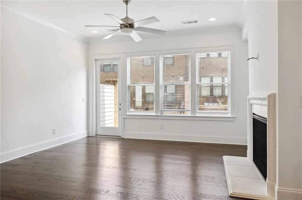 Unfurnished living room featuring crown molding, dark wood-type flooring, and ceiling fan