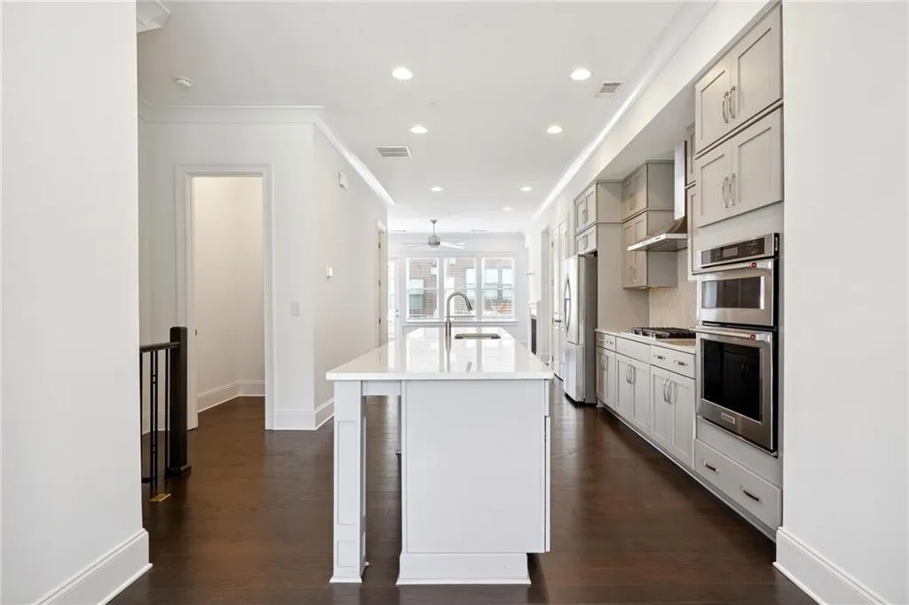 Kitchen featuring a kitchen island with sink, stainless steel appliances, sink, and dark hardwood / wood-style flooring