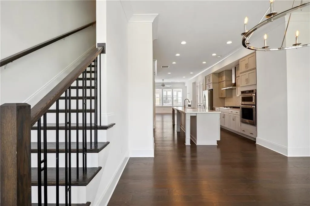 Stairway featuring ornamental molding, hardwood / wood-style flooring, and ceiling fan with notable chandelier