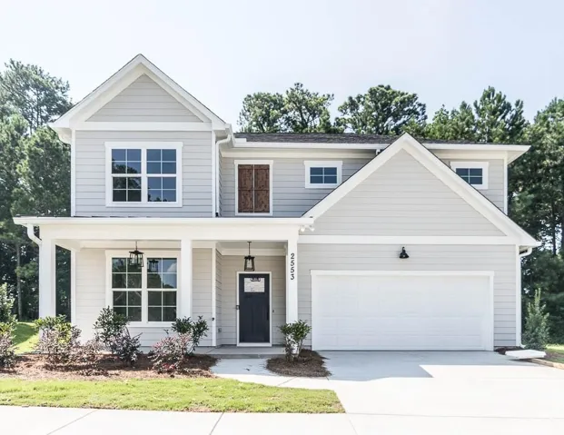 Two-story exterior with light gray siding, white trim, attached front porch, dark front door, and an integrated two-car garage