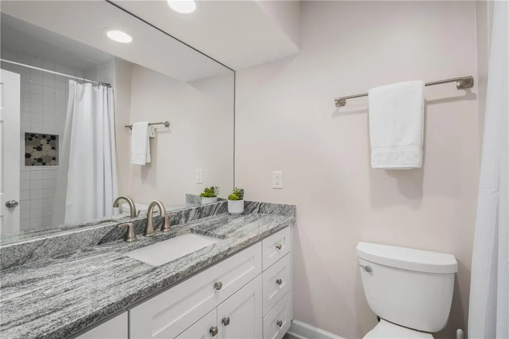 900 Edgewater Drive~ Recently renovated bathroom showcases granite counters, shaker cabinetry, and a tiled shower.