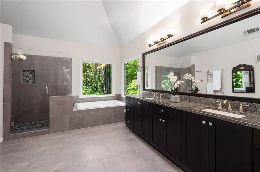 900 Edgewater Drive~ Recently renovated to perfection, this Primary bathroom offers a spacious and stylish shower, large soaking tub and gorgeous cherry cabinets with granite counters.
