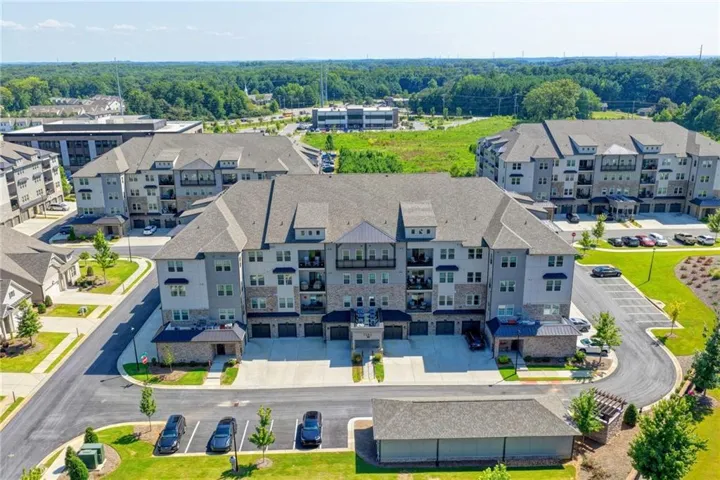 Modern multi-story apartment building with balconies, individual garages, and ample surface parking