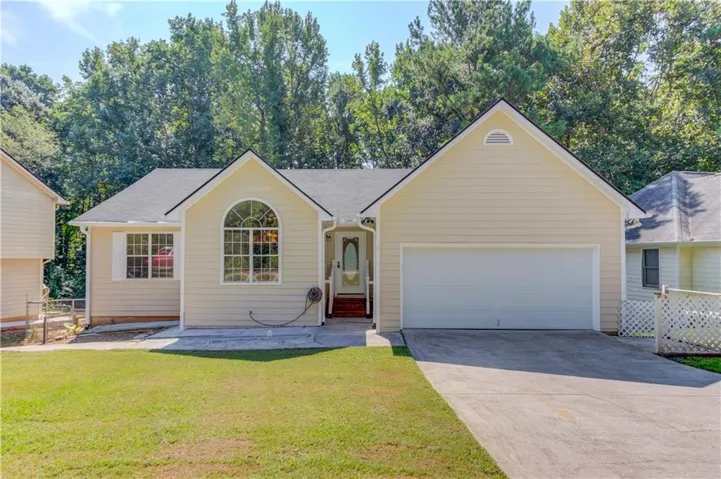 Light-colored siding exterior with an arched window, a two-car garage, and a concrete driveway