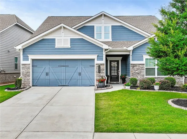 View of front facade featuring stone siding, driveway, and a garage