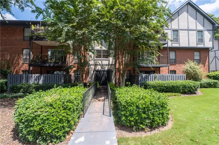 Brick and timber-frame exterior with multiple balconies, a pedestrian walkway, and manicured landscaping