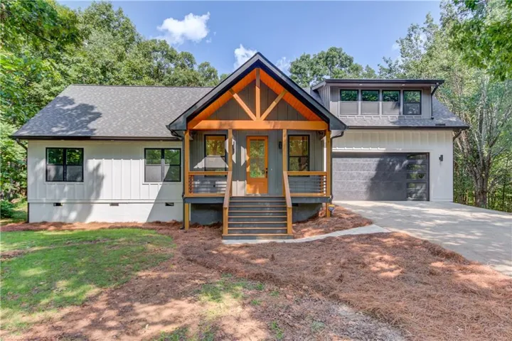 Modern farmhouse exterior featuring an exposed beam entryway and a dark gray garage door