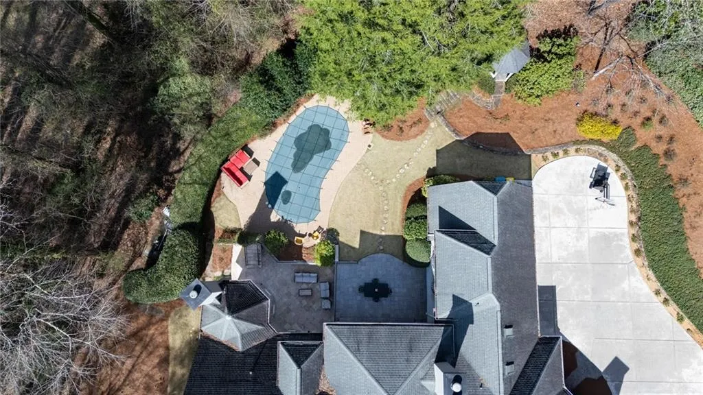 This stunning aerial view highlights the home s beautifully landscaped grounds, showcasing the private pool, expansive patio, and serene wooded surroundings.